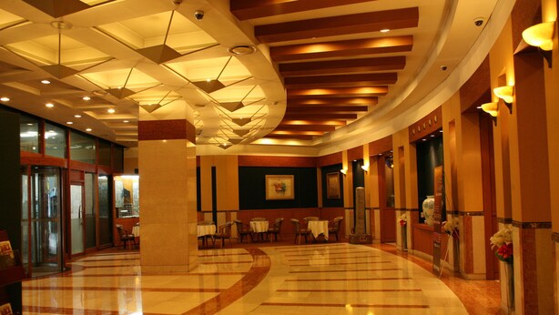 A spacious lobby with a polished marble floor, a large central column, and a curved ceiling with geometric light fixtures. - Hotel Samwon Plaza (Anyang)