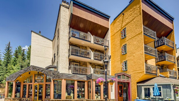 A multi-story building with balconies, a storefront with a sign, and outdoor seating. - Lift House Lodge (Vail)