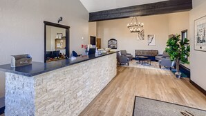 A spacious living area with a stone reception desk, modern furniture, and a large chandelier. - Lift House Lodge (Vail)