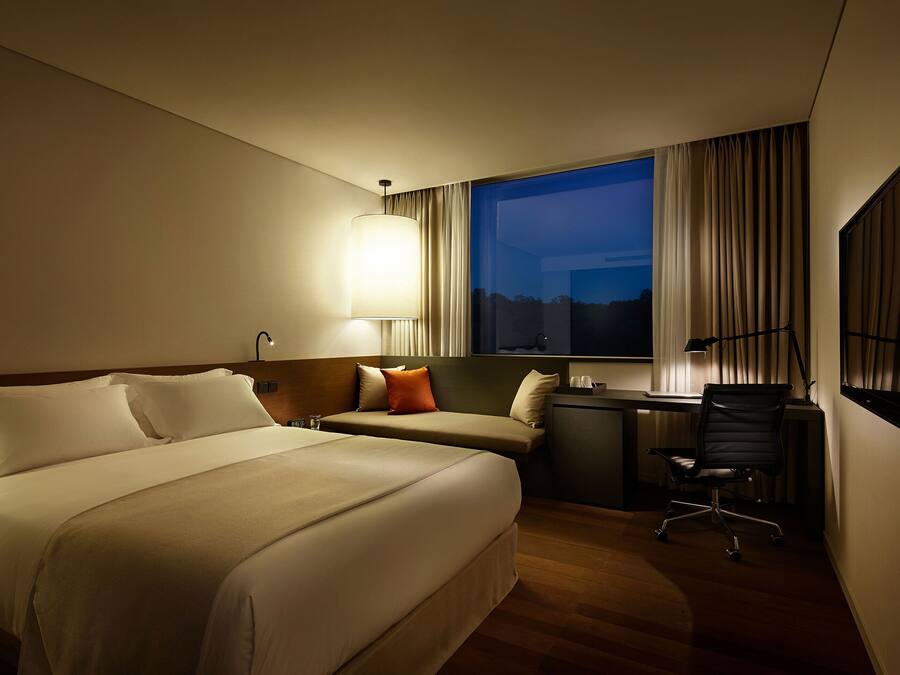 A hotel room with a large bed, a desk, and a chair.