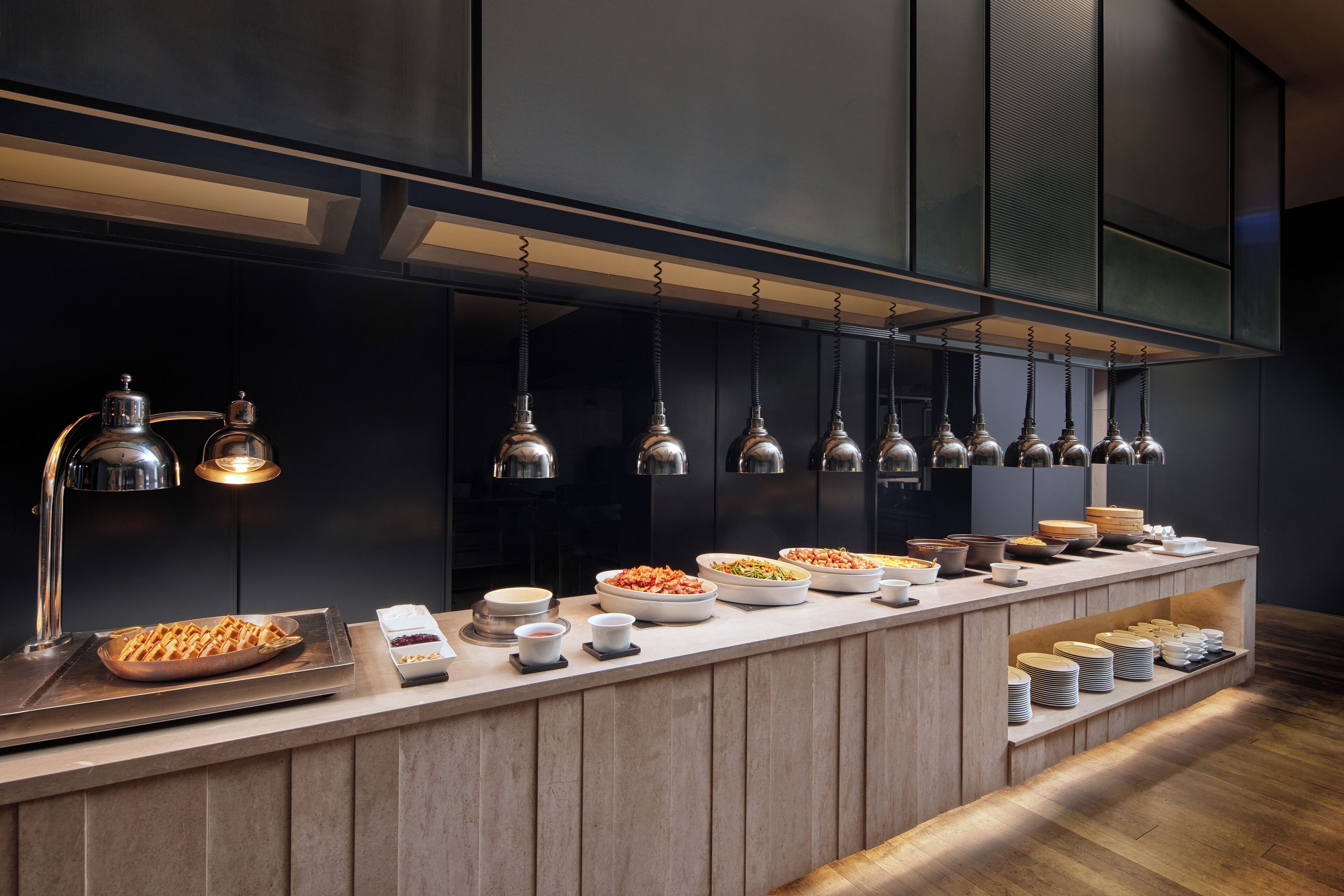 A buffet setup with various food items and a modern kitchen backdrop.