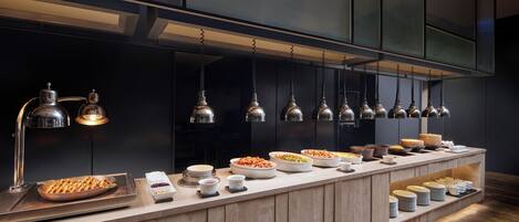 A buffet setup with various food items and a modern kitchen backdrop.