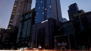 A high-rise hotel with a modern glass facade, multiple floors, and illuminated windows. - Shilla Stay Dongtan (Hwaseong)