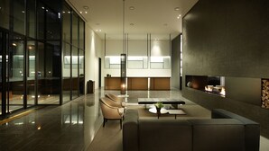 A modern lounge area with a sofa, chairs, a coffee table, and a fireplace. - Shilla Stay Dongtan (Hwaseong)