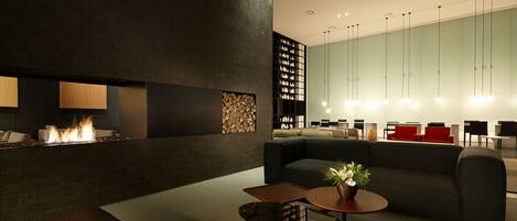 Un espacio lounge moderno con chimenea, asientos y una mesa de centro.