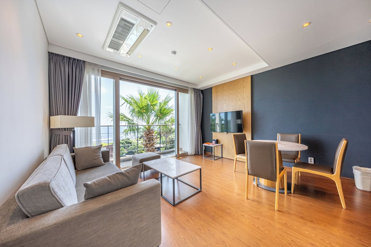 A modern living room with a sofa, coffee table, and dining area with chairs.