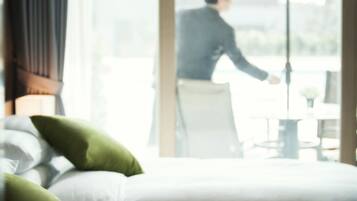 A hotel room with a bed, pillows, and a view of a person outside.