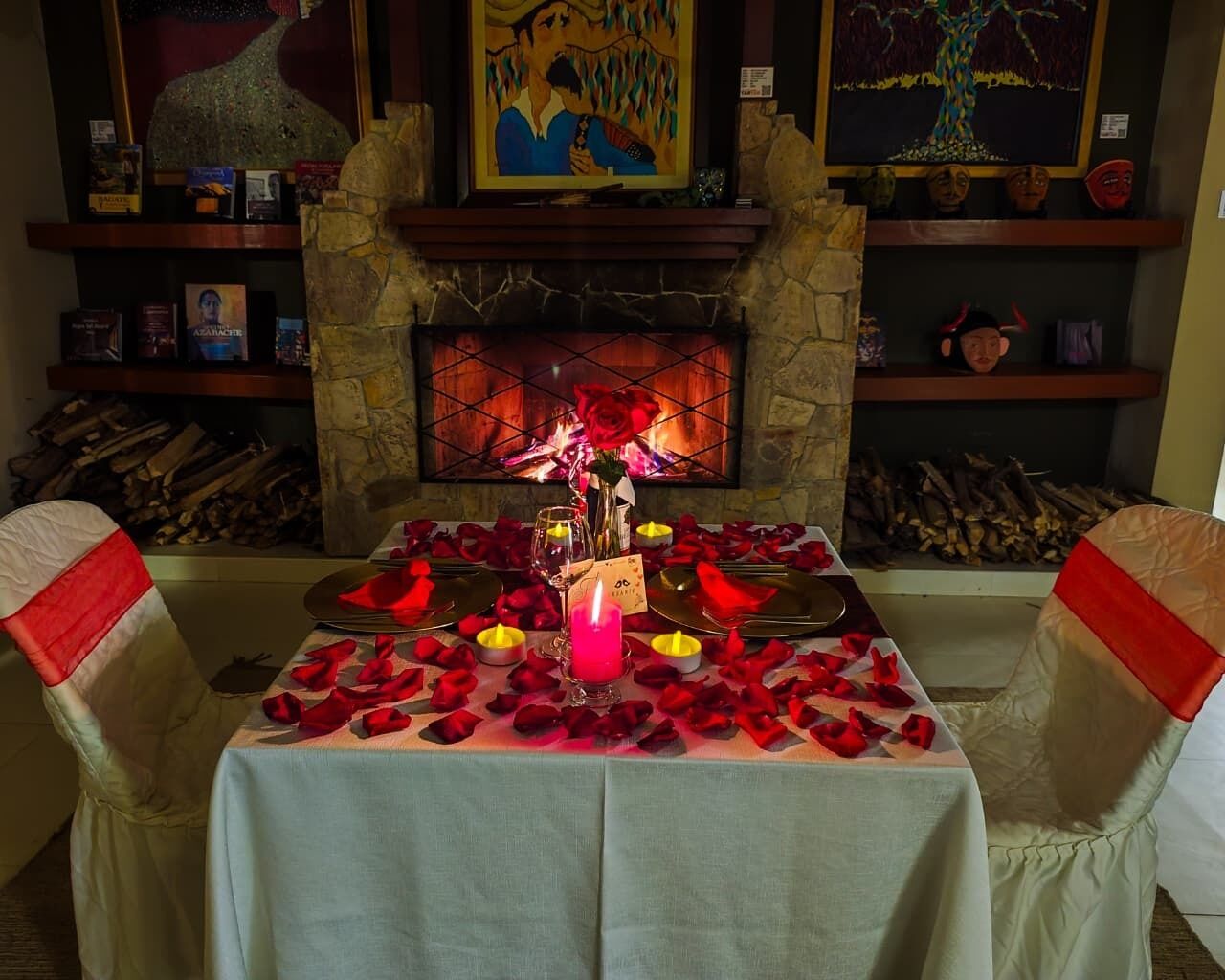 Una cena romántica con chimenea, pétalos de rosa y velas.