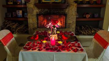Una cena romántica con chimenea, pétalos de rosa y velas.