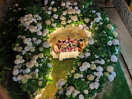 Disposición circular de asientos rodeada de exuberantes arbustos de hortensia, con una mesa lista para una comida.