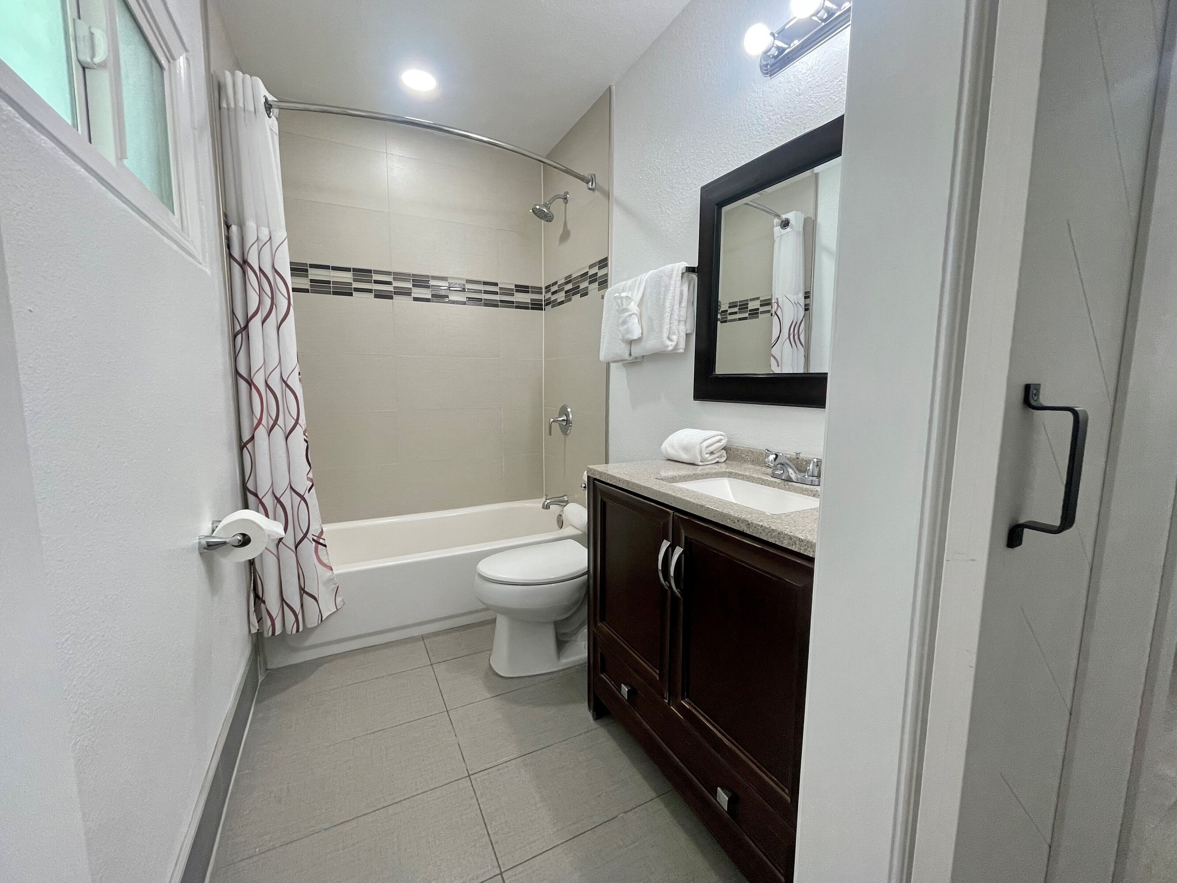 A compact bathroom with a shower, toilet, and vanity.