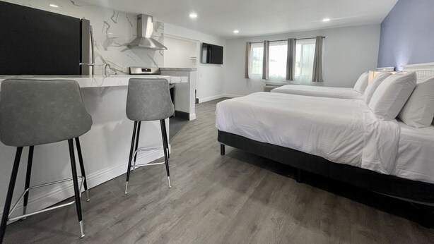 A modern hotel room with a kitchenette, a large bed, and two bar stools. - Budget Inn Lompoc (Lompoc)