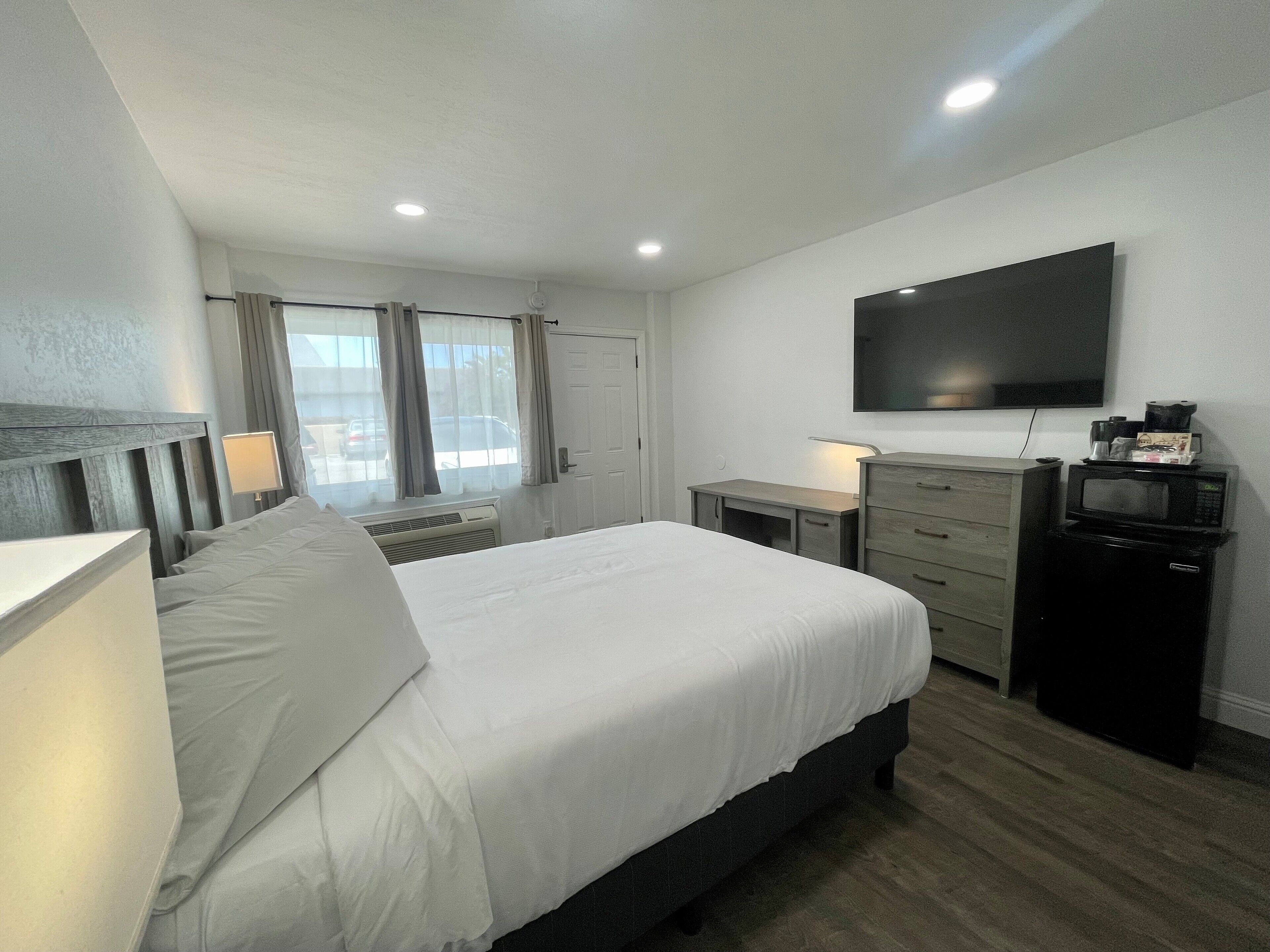 A hotel room with a bed, a desk, a television, and a microwave.