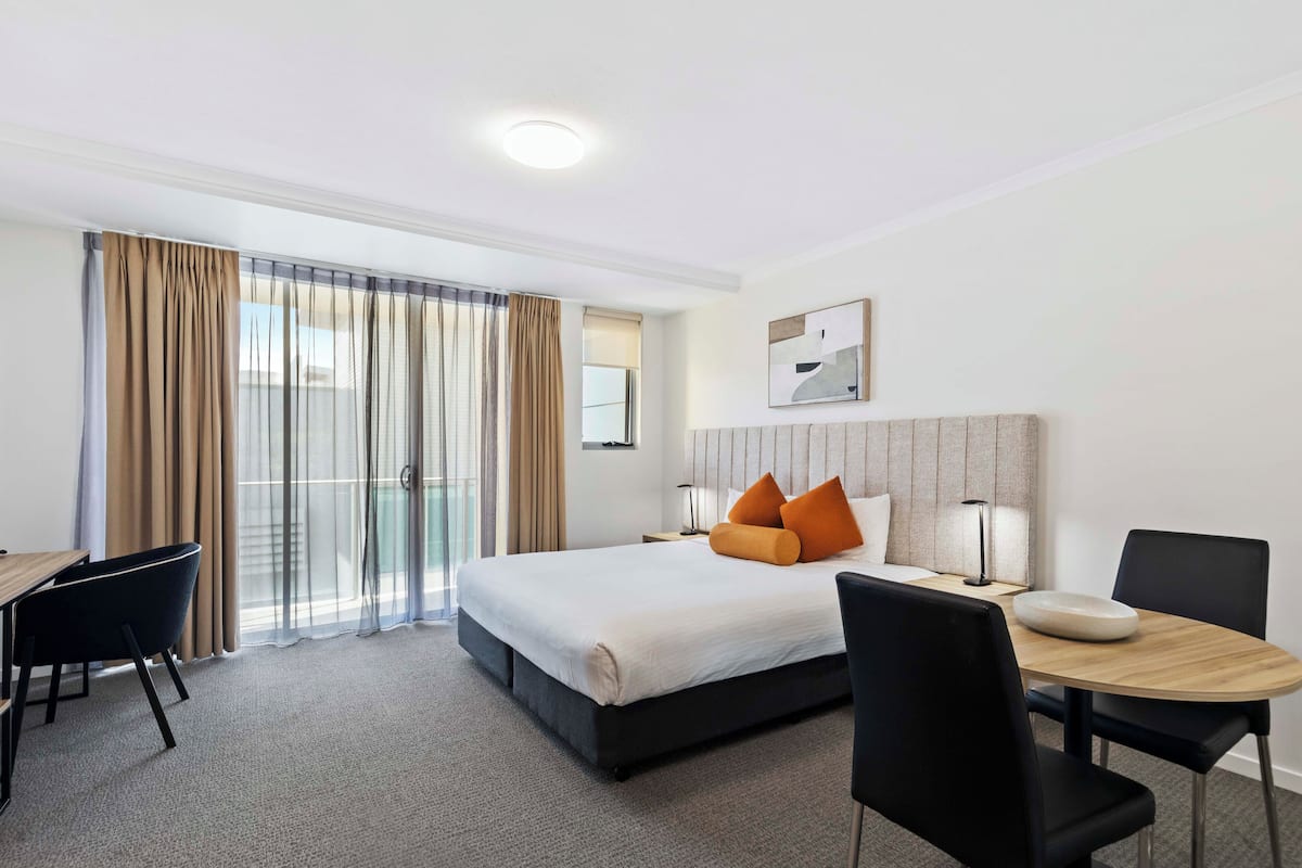 A hotel room with a bed, a desk, a chair, and a table.
