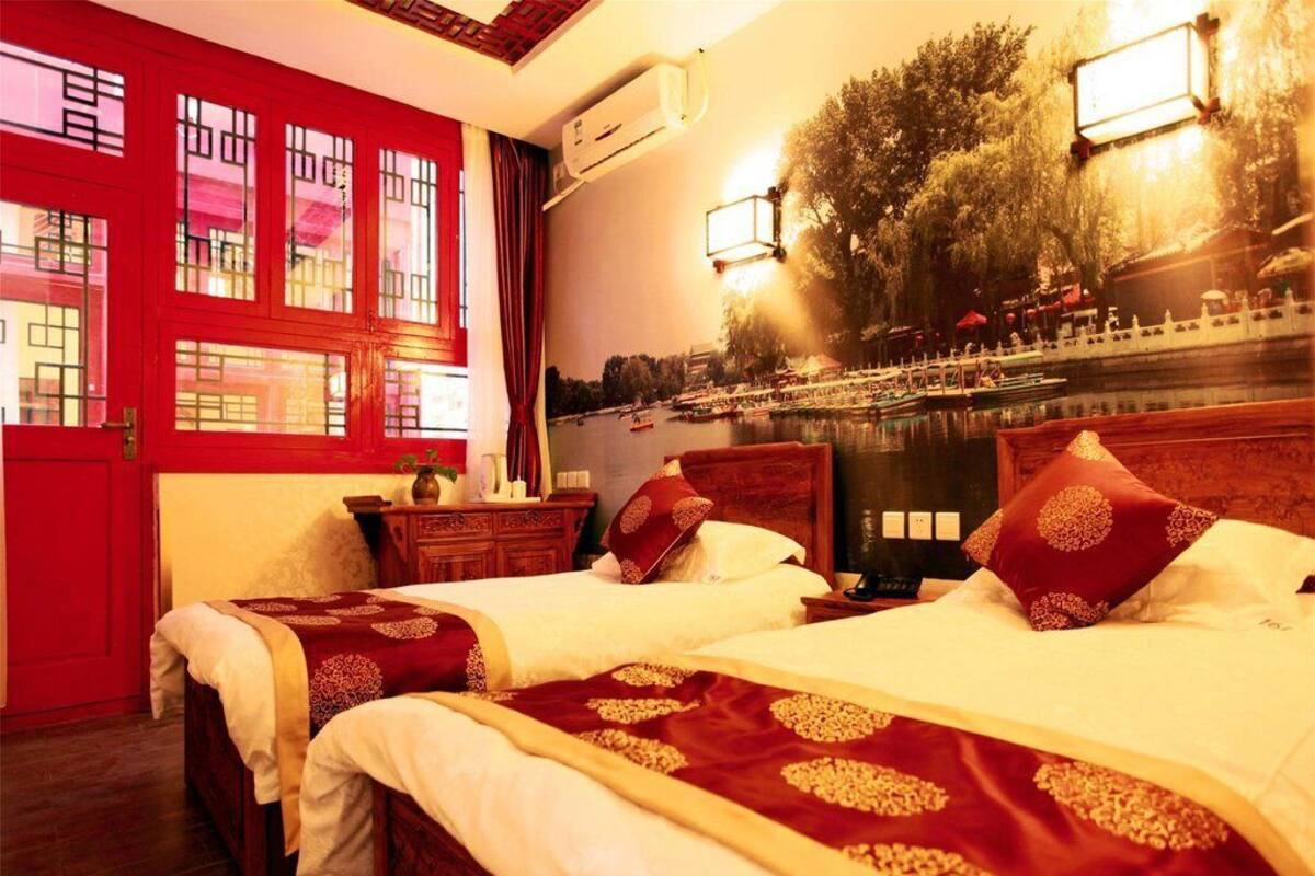 A hotel room with two beds, a red door, and a mural of a river scene.