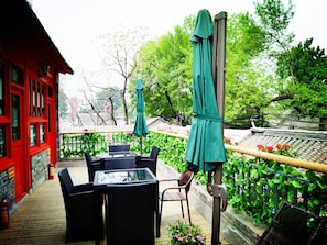 An outdoor seating area with tables and chairs, a red building, and a traditional fence. - 161 Lama Temple Courtyard Hotel (Beijing)