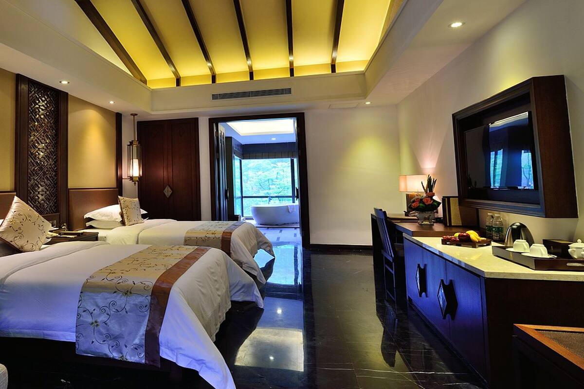 Une chambre d’hôtel avec deux lits, une salle de bain, un coin salon et un comptoir de cuisine.