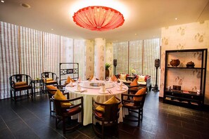 A dining area with a round table set for four, surrounded by wooden chairs with yellow cushions. - Beijing Hotel MOMC (Beijing)