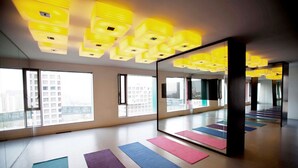 A spacious room with large windows, a mirrored wall, and exercise mats on the floor. - Beijing Hotel MOMC (Beijing)