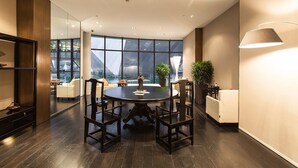 A modern conference room with a round table, chairs, and a large window offering a city view. - Beijing Hotel MOMC (Beijing)