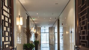 A corridor with dark wooden flooring, mirrored walls, and potted plants. - Beijing Hotel MOMC (Beijing)