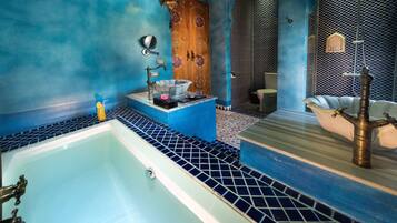 A bathroom with a large bathtub, a wooden door with intricate designs, and a patterned wall.