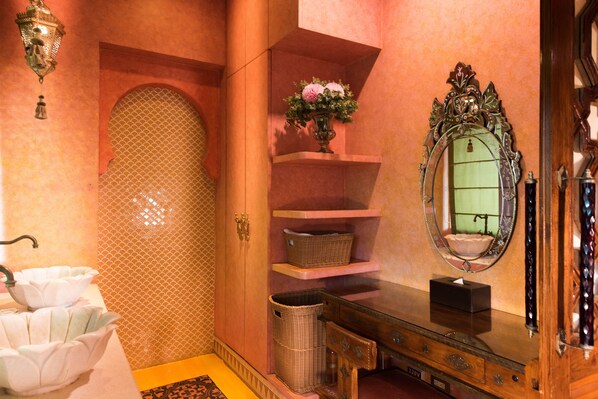 A bathroom with a white sink, a mirror, a vase with flowers, and wicker baskets. - Amanda Hotel Kenting (Hengchun)