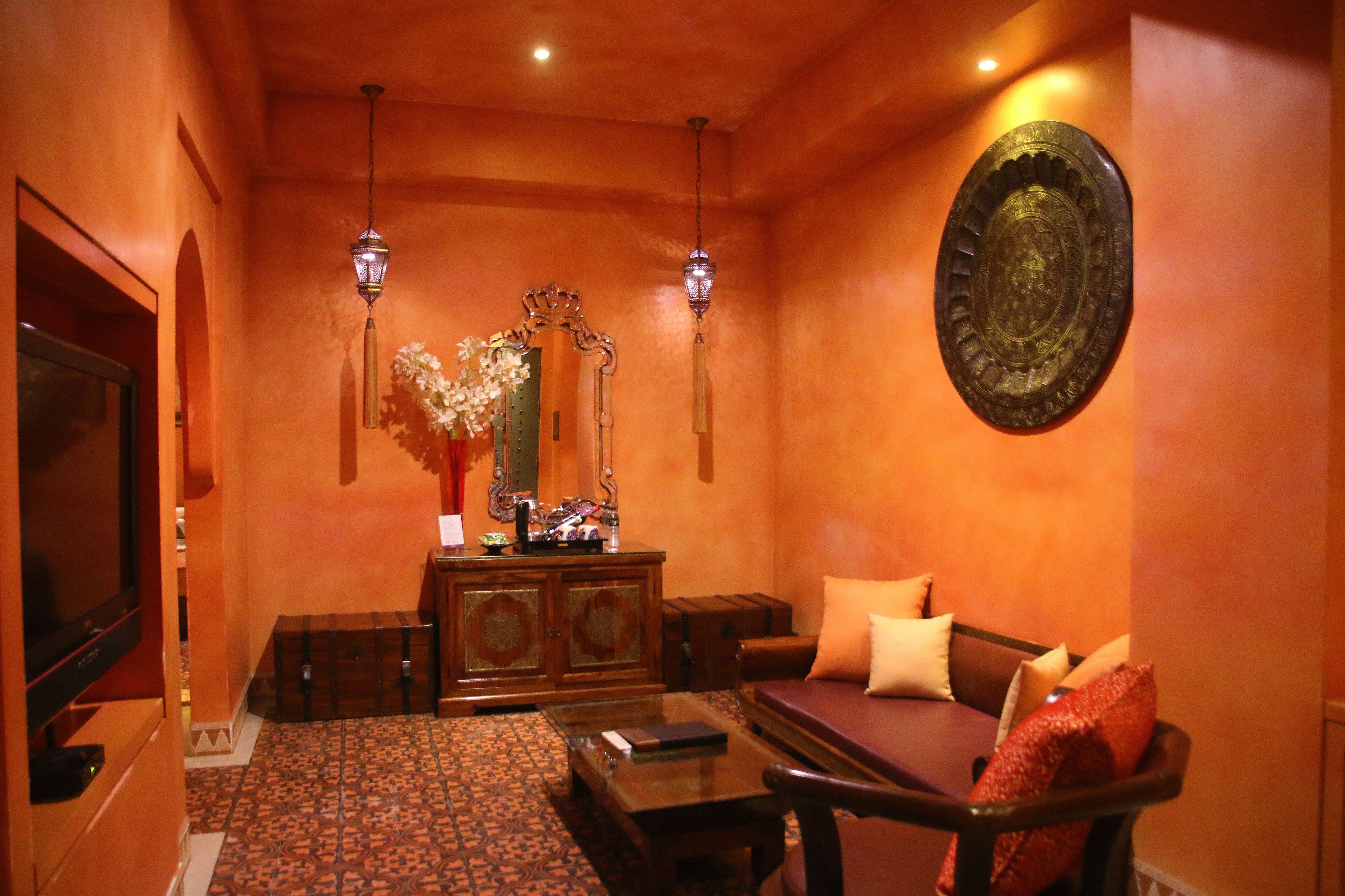 A warmly lit room with a sofa, a wooden cabinet, and a decorative mirror.