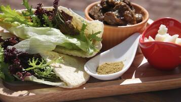 A wooden tray with a wrap containing lettuce, a bowl of meat, a small bowl of seasoning, and a red bowl with a white substance.