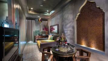 A room with a sofa, a coffee table, a television, and a decorative wall.