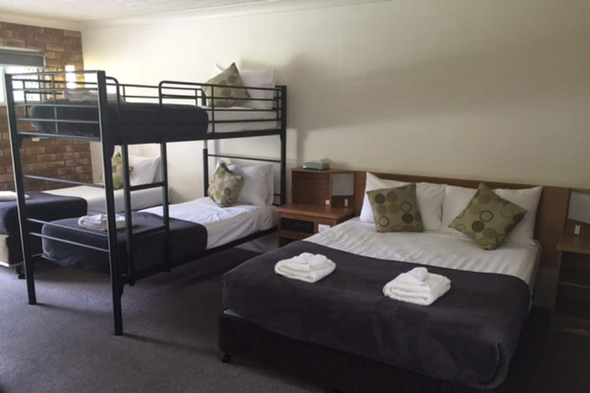 A room with bunk beds, a single bed, and a bedside table.