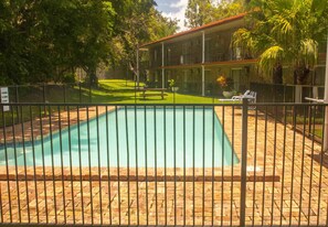 A swimming pool with a brick border, surrounded by a fence.