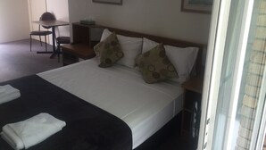 Una habitación de hotel con cama, escritorio, silla y puerta.