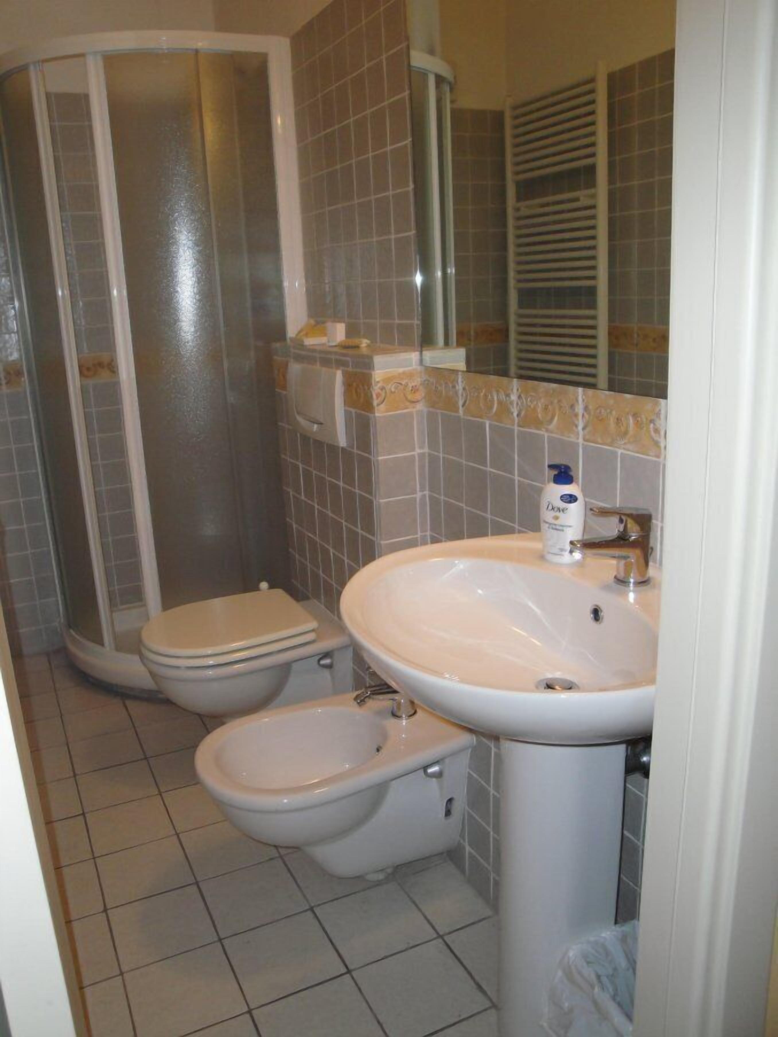 Ein Badezimmer mit Dusche, zwei Toiletten und einem Waschbecken.
