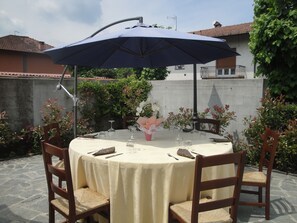 An outdoor dining area with a round table, chairs, and a large umbrella. - Locanda del Brinsc (Brinzio)