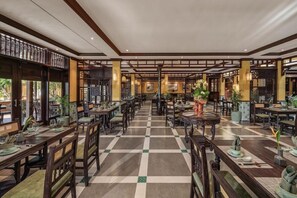 Een ruime hotellobby met zwart-witte vloertegels, houten meubels en een decoratieve fontein in het midden.