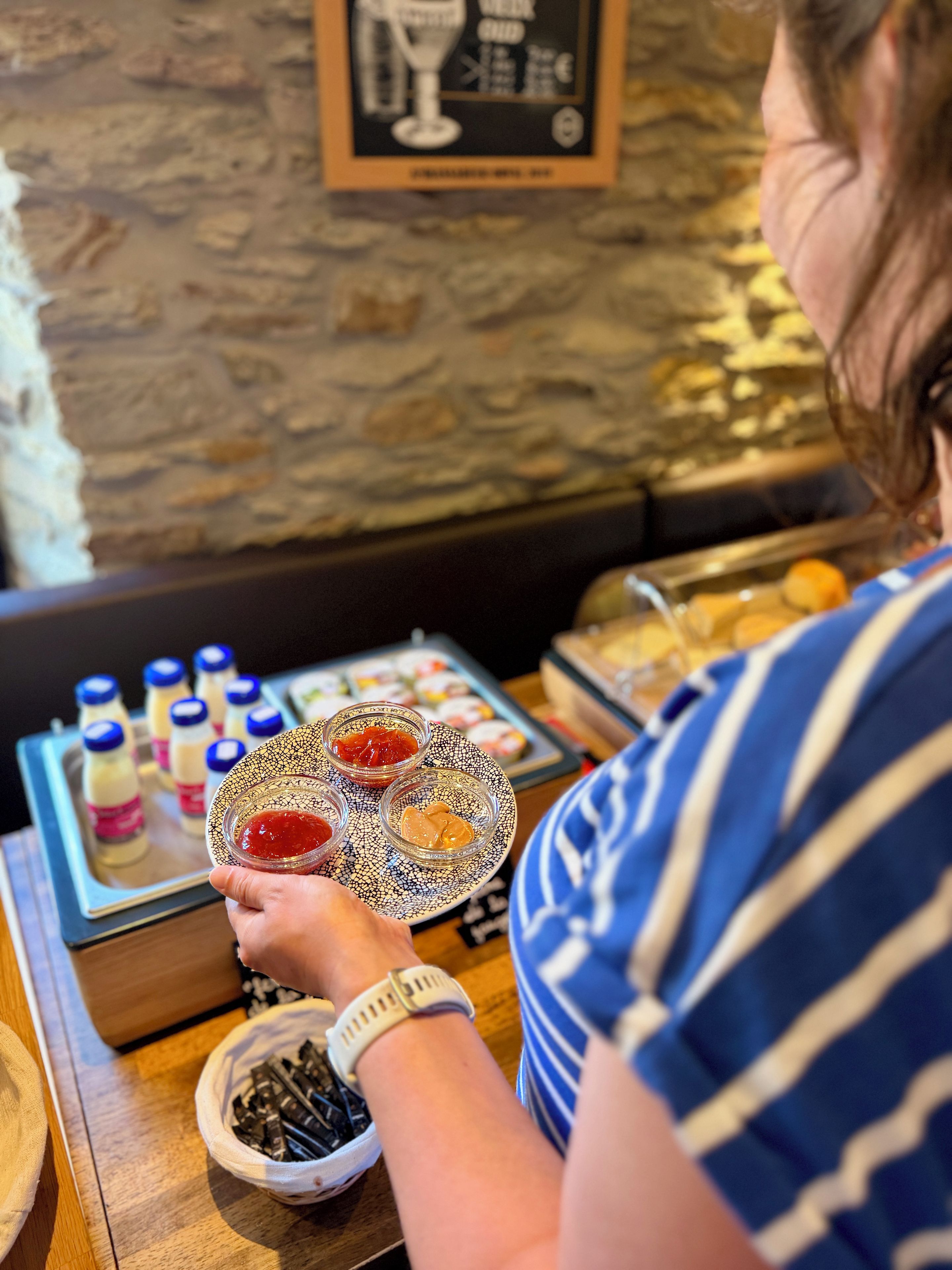 A person holding a plate with condiments, a tray with bottles, and a bowl of chocolate pieces.