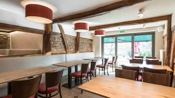 Interior de restaurante con mesas y sillas de madera, paredes de ladrillo visto e iluminación colgante.