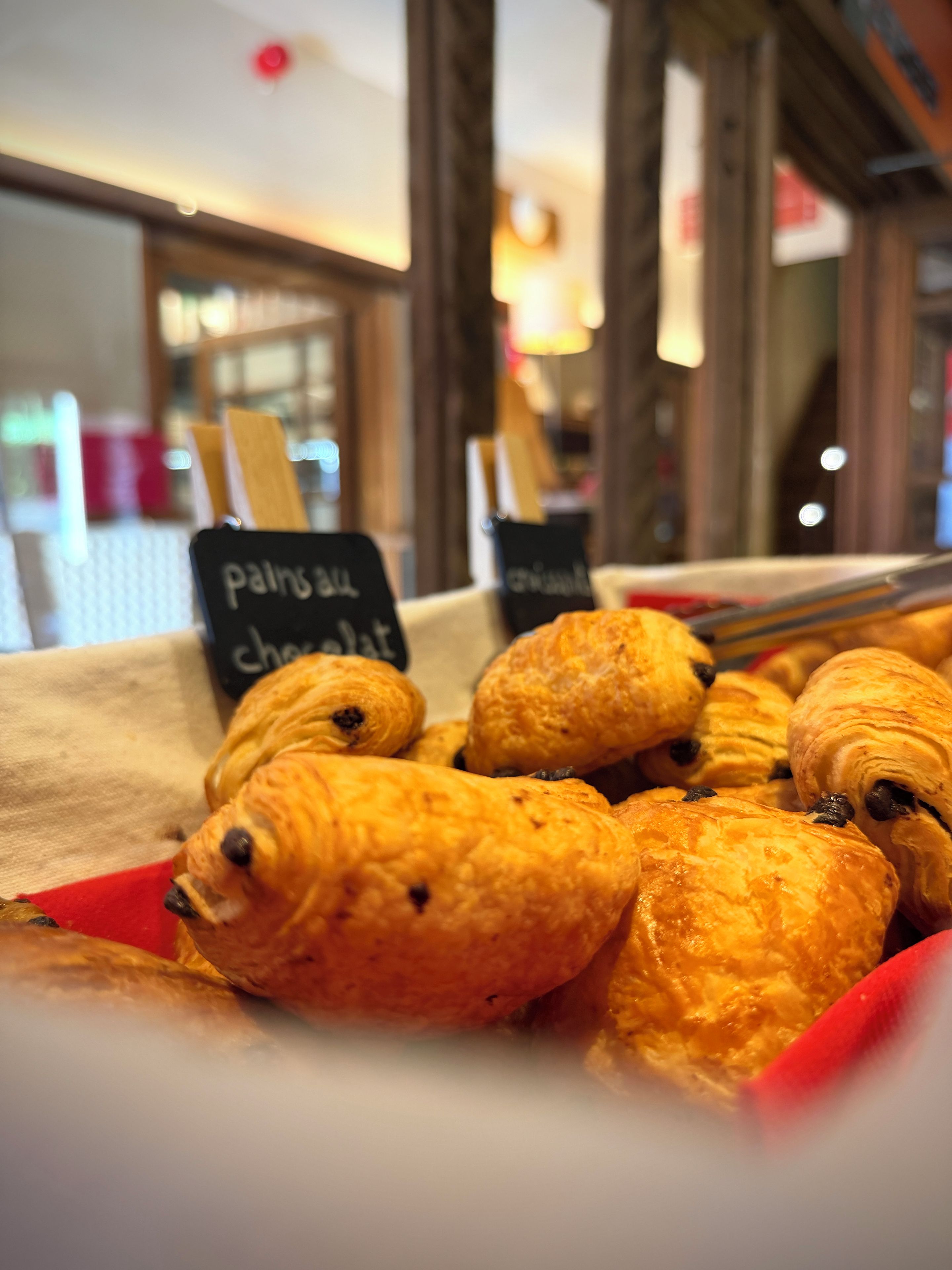 Una exhibición de pastelería con letreros que indican 'pains au chocolat' y 'chocolat'.