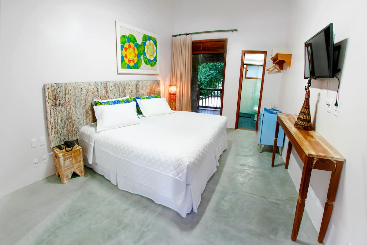 A bedroom with a bed, a bedside table, a TV, and a painting on the wall.