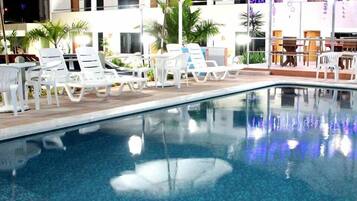 Una piscina techada, una piscina al aire libre, sombrillas