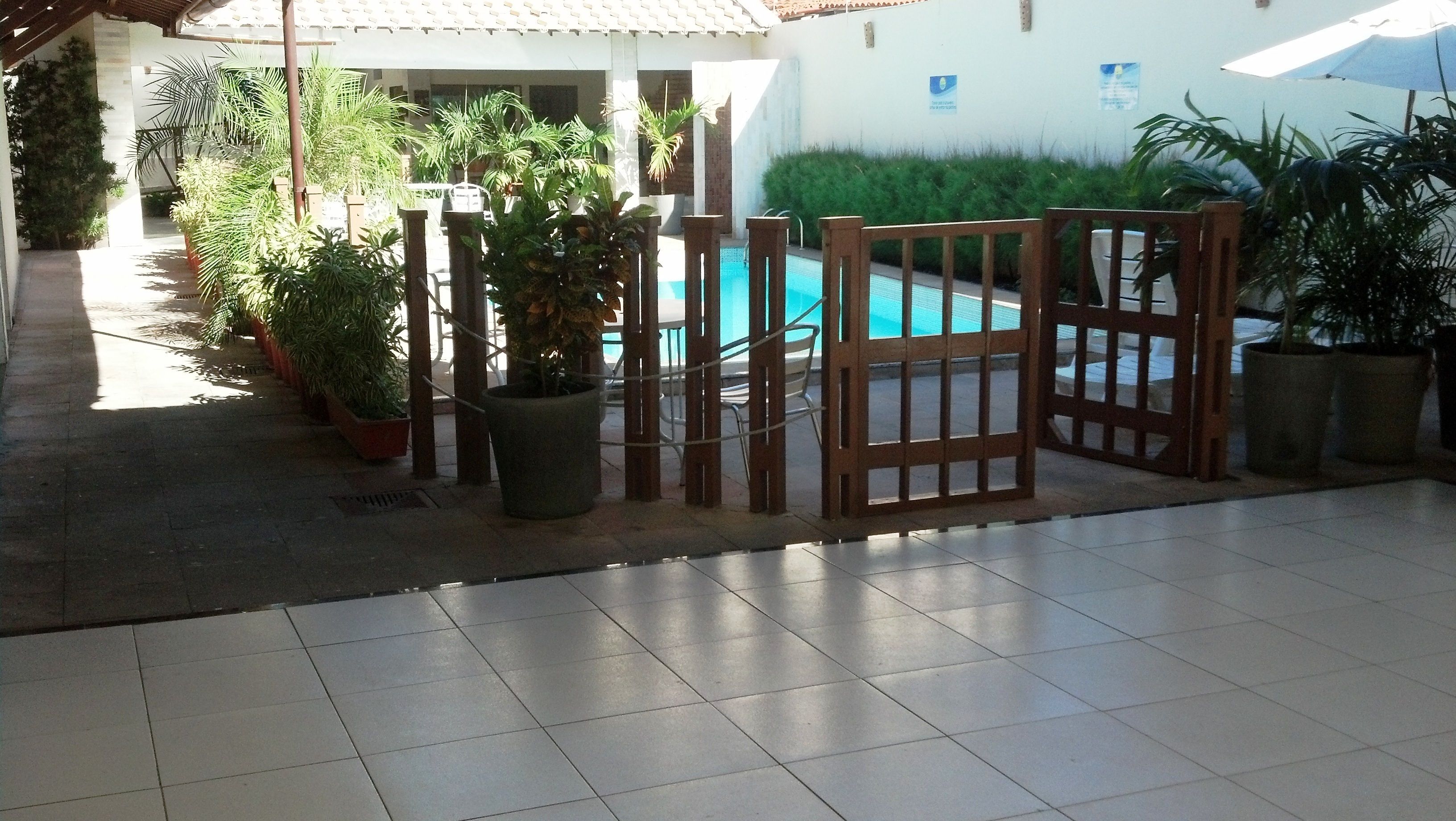 A pool area with a tiled floor, potted plants, and a wooden gate.