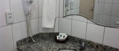 Un baño con encimera de granito, un lavabo blanco, un secador de pelo y una toalla colgada en la pared.