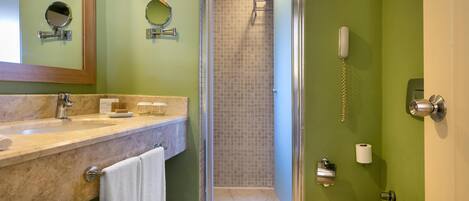 A bathroom with a sink, mirror, toilet, and shower.