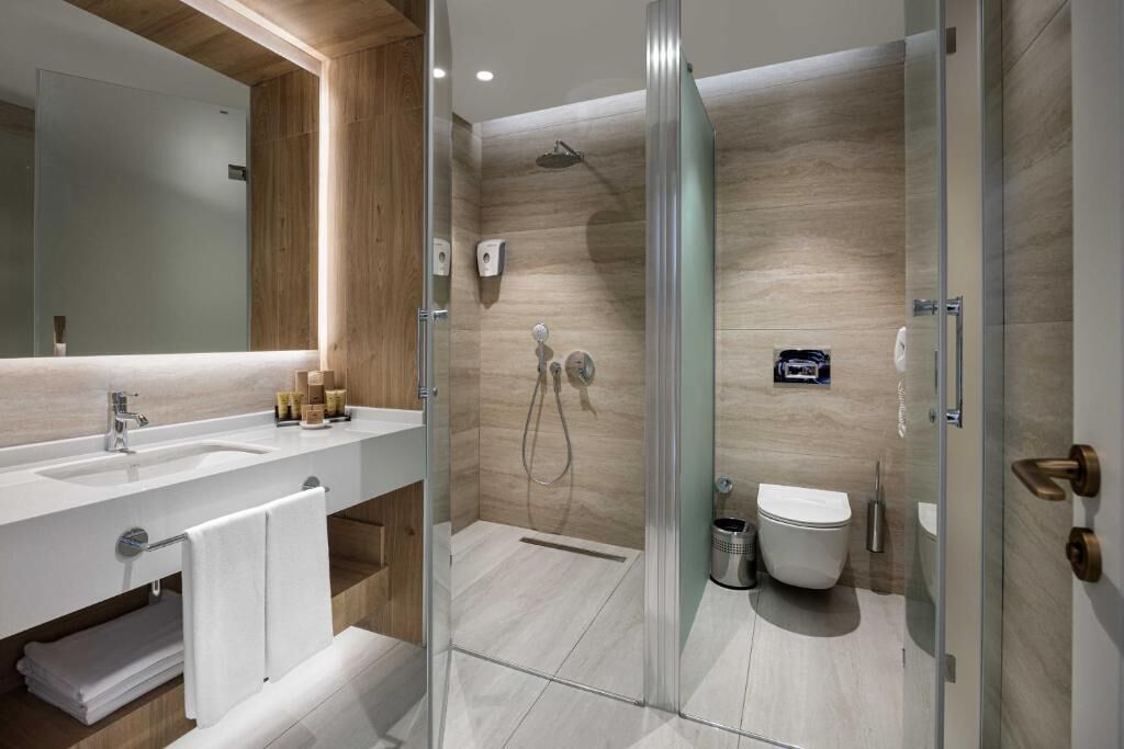 A modern bathroom with a glass-enclosed shower, a white sink, and a toilet.
