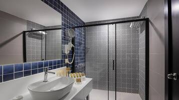 Un baño moderno con un lavamanos grande, espejo y cabina de ducha.