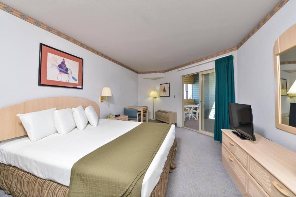 A hotel room with a bed, a desk, a television, and a mirror.