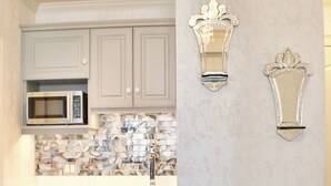 A kitchen with white cabinets, a microwave, a dishwasher, and a patterned backsplash. - Billy Barker Casino Hotel (Quesnel)