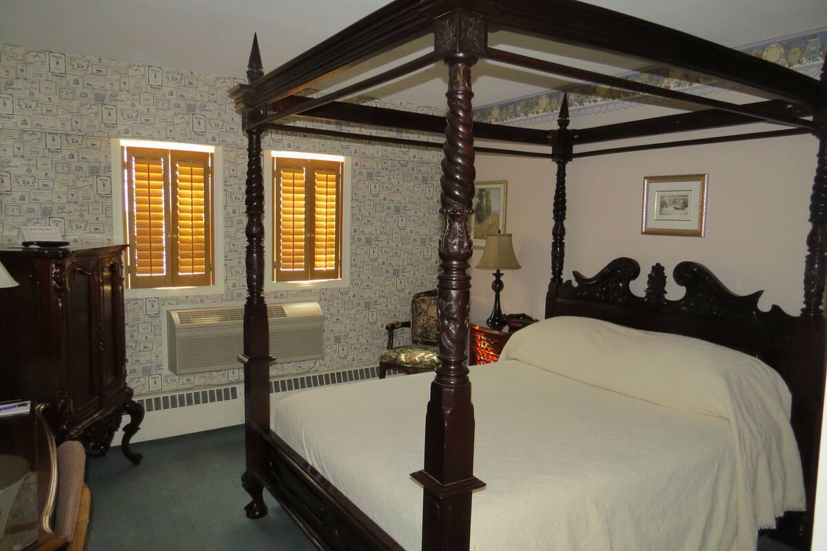 A four-poster bed with a canopy, a desk with a chair, and a radiator.