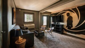 A modern living room with a sofa, a coffee table, a TV, and a unique wall mural. - Billy Barker Casino Hotel (Quesnel)